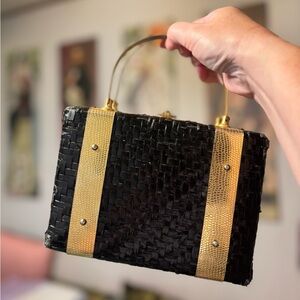 Small black basket weave bag with sturdy gold handles.